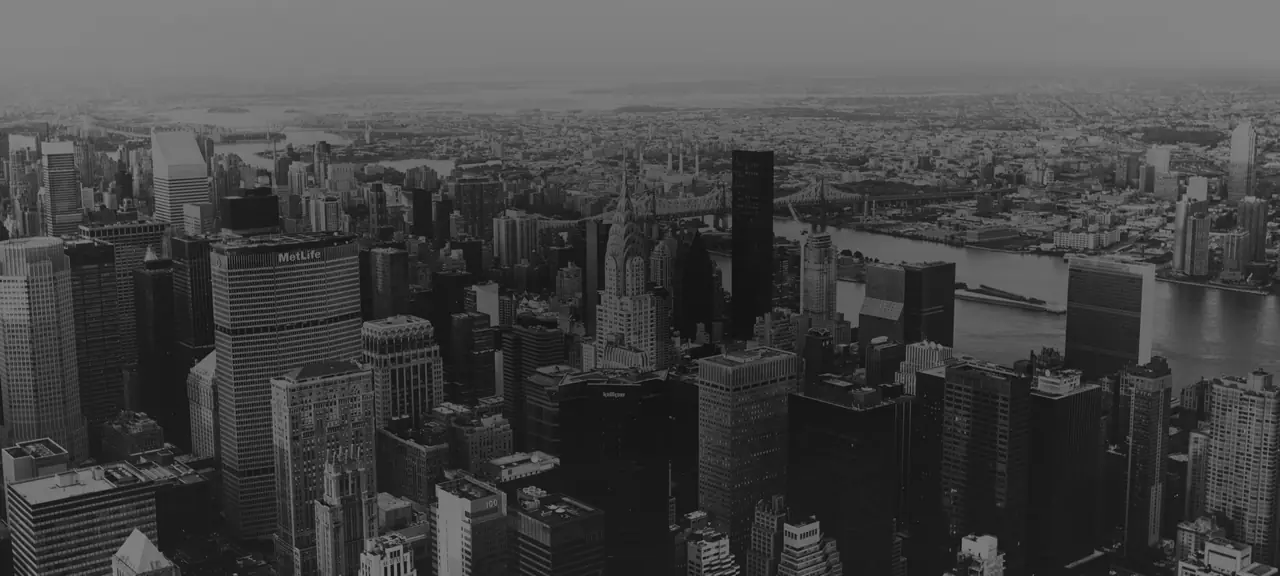 Black-and-white aerial view of a city skyline with tall office towers beside a river